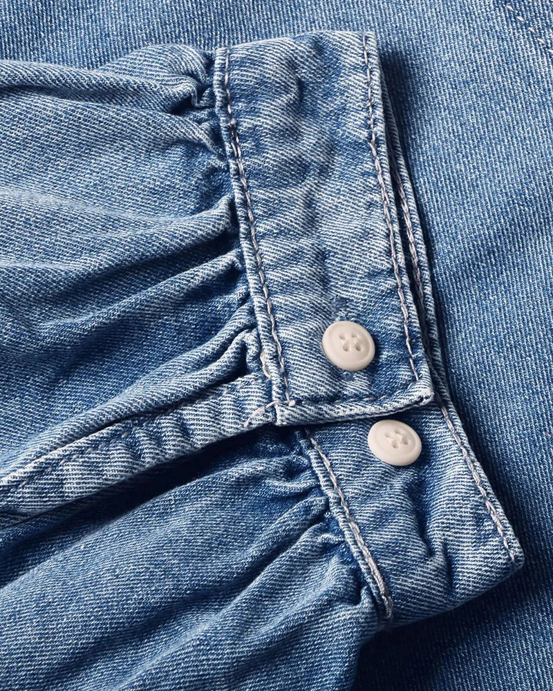 Detailaufnahme von Kragen, Druckknöpfen und Denimstoff der Jeansbluse